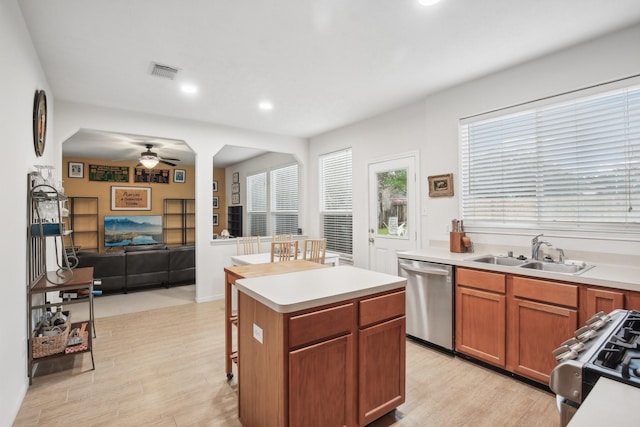 kitchen featuring a kitchen island, sink, light wood-type flooring, stainless steel dishwasher, and gas range oven