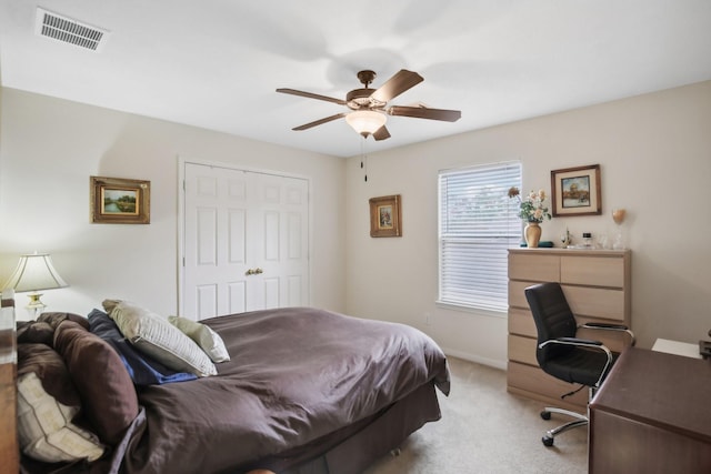 bedroom with light colored carpet, ceiling fan, and a closet