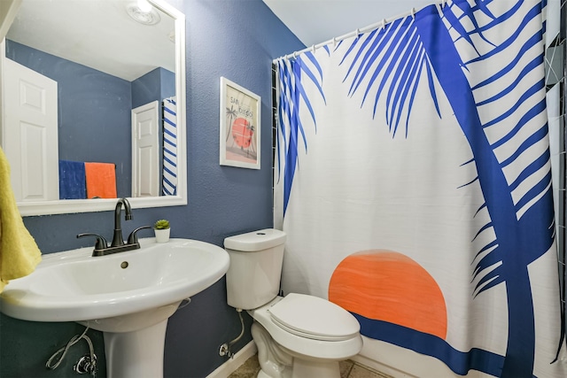 full bathroom featuring curtained shower, toilet, a textured wall, and a sink