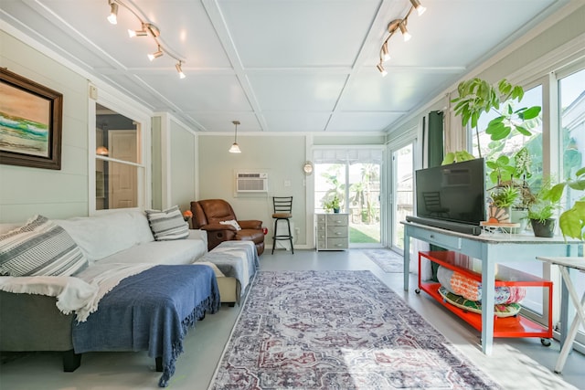 living area with a wall mounted air conditioner, finished concrete floors, and rail lighting