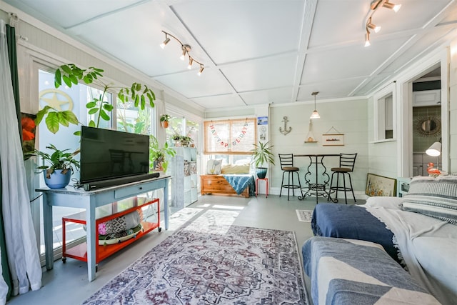 living area featuring rail lighting, finished concrete flooring, and a sunroom