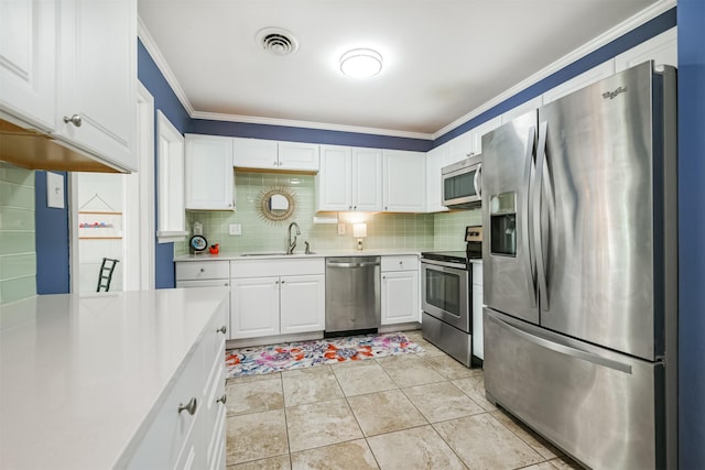 kitchen with white cabinets, appliances with stainless steel finishes, ornamental molding, and sink