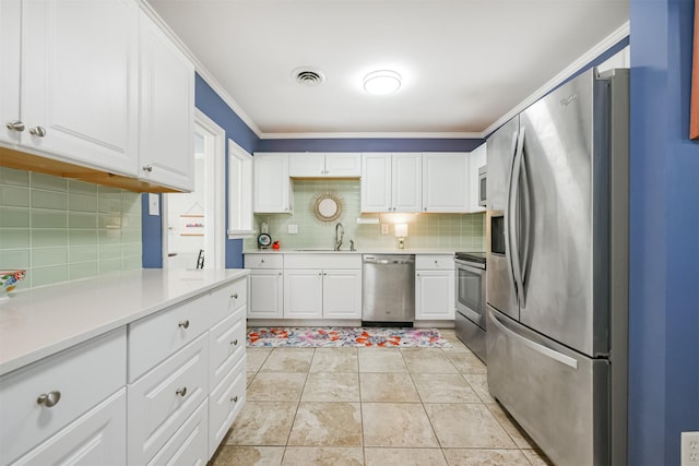 kitchen with white cabinets, appliances with stainless steel finishes, decorative backsplash, sink, and ornamental molding