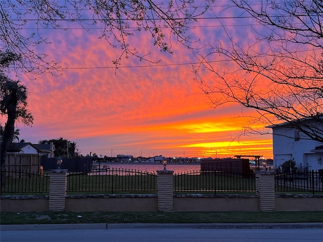 gate at dusk featuring a water view