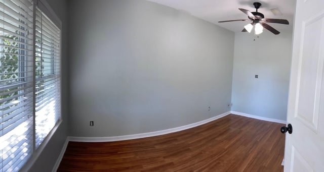 spare room featuring baseboards, plenty of natural light, dark wood-type flooring, and a ceiling fan