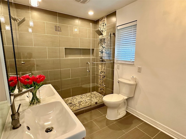 bathroom featuring tile patterned floors, toilet, dual sinks, and walk in shower