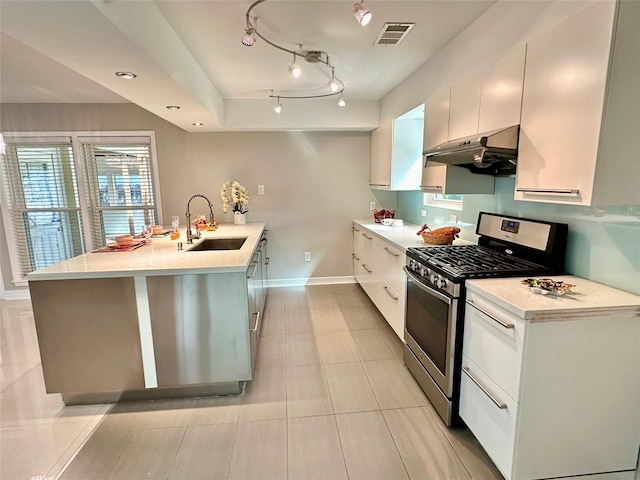 kitchen featuring white cabinets, light tile patterned flooring, stainless steel gas range oven, and sink