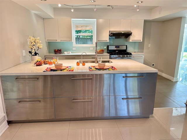 kitchen featuring gray cabinetry, stainless steel gas range oven, light tile patterned flooring, and sink