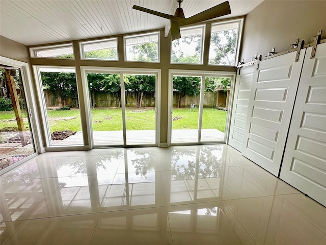 doorway featuring light tile patterned floors, a barn door, and ceiling fan