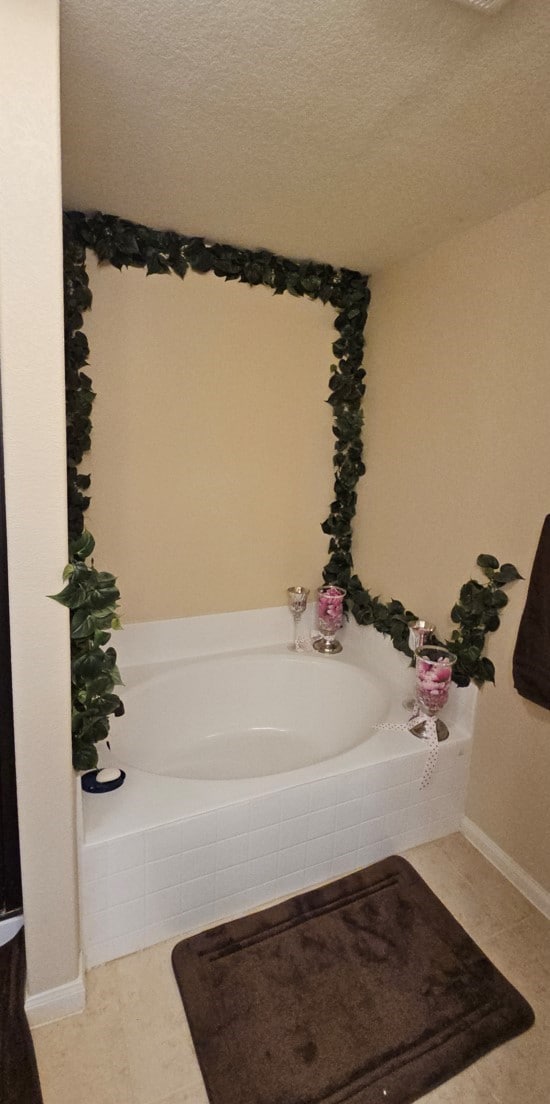 bathroom featuring a textured ceiling, tiled bath, and tile patterned floors