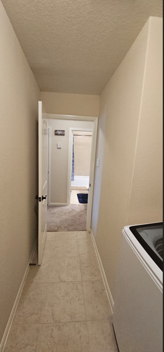 corridor with light tile patterned flooring and a textured ceiling