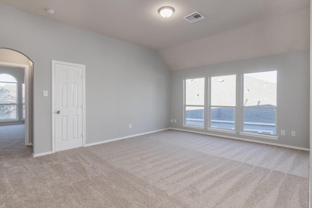 empty room featuring vaulted ceiling and light colored carpet