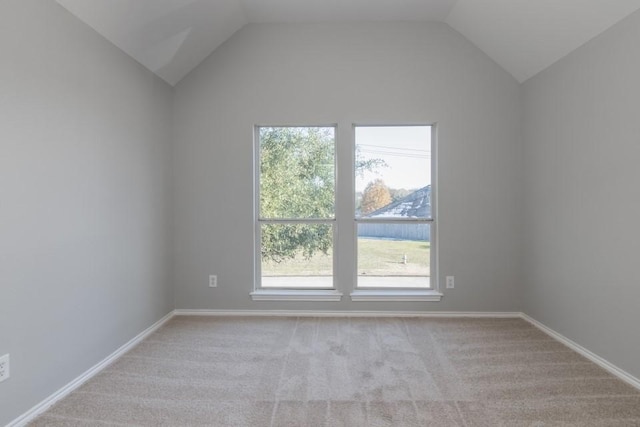 empty room with vaulted ceiling and light colored carpet