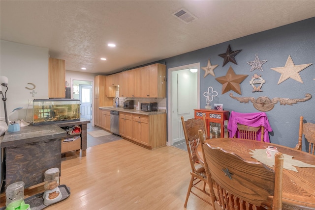 dining room with a textured ceiling, light hardwood / wood-style floors, and sink