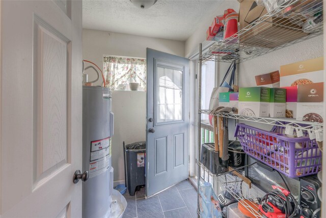 laundry room with a textured ceiling and electric water heater