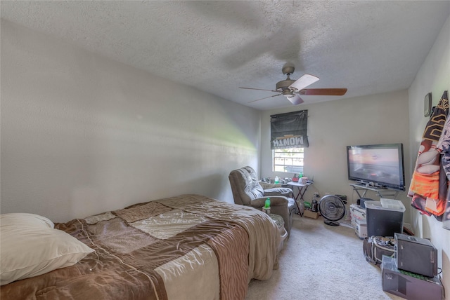 carpeted bedroom featuring ceiling fan and a textured ceiling