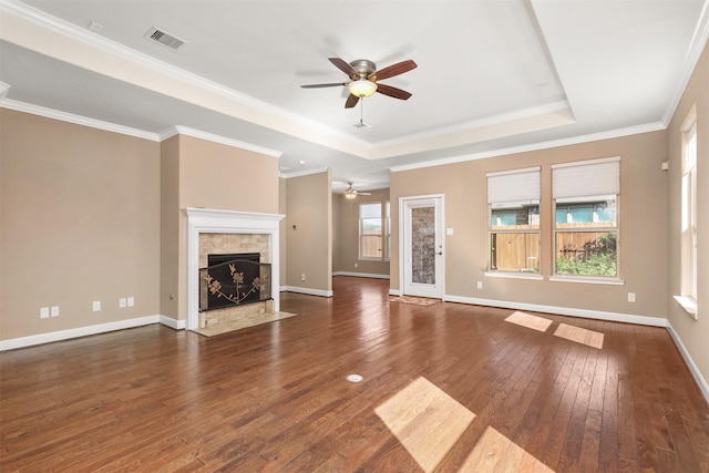 unfurnished living room featuring dark hardwood / wood-style floors, crown molding, a tray ceiling, and a healthy amount of sunlight