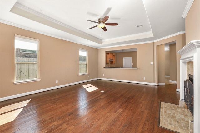 unfurnished living room with dark hardwood / wood-style floors, a healthy amount of sunlight, and a tray ceiling