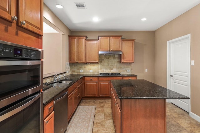 kitchen with dark stone countertops, sink, a center island, and appliances with stainless steel finishes