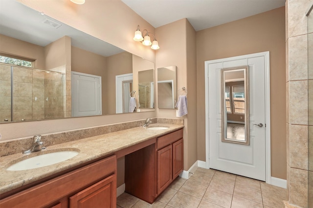 bathroom with tile patterned floors, vanity, and a tile shower