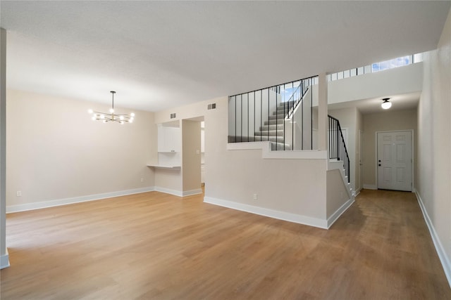 1300 Augusta Dr Unit 12, Houston, TX 77057 - unfurnished living room featuring a chandelier, light wood-style floors, and stairway