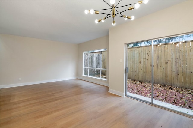 unfurnished room featuring hardwood / wood-style flooring and an inviting chandelier