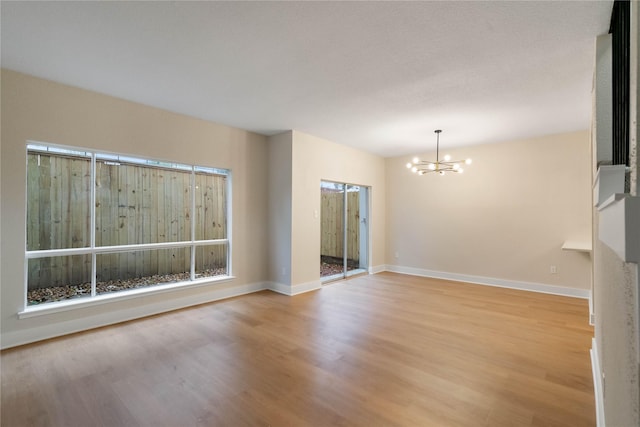 empty room with light wood-type flooring and a chandelier