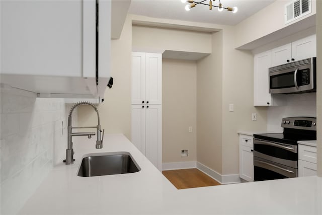 1300 Augusta Dr Unit 12, Houston, TX 77057 - kitchen with appliances with stainless steel finishes, light countertops, white cabinets, a chandelier, and decorative backsplash