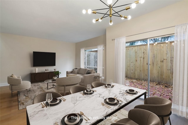 dining area with a healthy amount of sunlight, light wood-type flooring, and an inviting chandelier