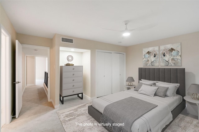 bedroom with ceiling fan, light carpet, and a closet