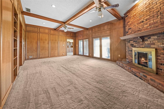 unfurnished living room with light carpet, a brick fireplace, beamed ceiling, a textured ceiling, and wooden walls