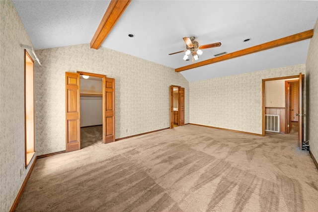 unfurnished bedroom featuring lofted ceiling with beams, carpet floors, a spacious closet, and ceiling fan