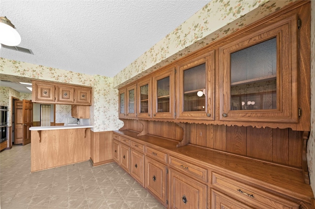 kitchen featuring kitchen peninsula, a textured ceiling, and stainless steel double oven