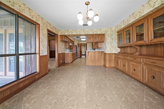 kitchen with a chandelier, a textured ceiling, hanging light fixtures, and wooden walls