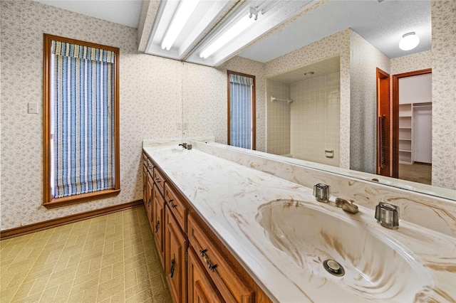 bathroom featuring a tile shower, vanity, and a textured ceiling