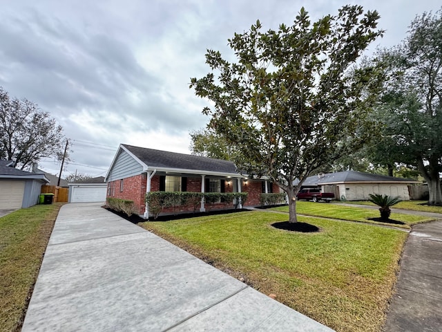 ranch-style home featuring an outbuilding, a front lawn, covered porch, and a garage