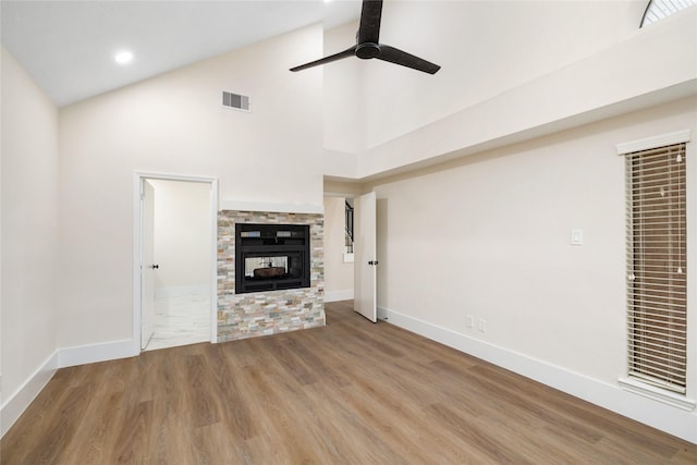 unfurnished living room with ceiling fan, a fireplace, high vaulted ceiling, and hardwood / wood-style flooring