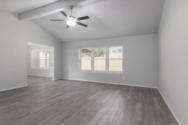 empty room with ceiling fan, plenty of natural light, dark hardwood / wood-style floors, and vaulted ceiling with beams