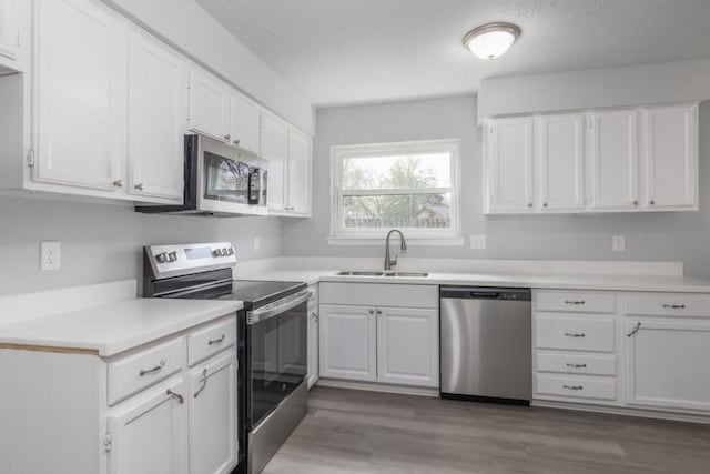 kitchen featuring hardwood / wood-style floors, stainless steel appliances, white cabinets, and sink