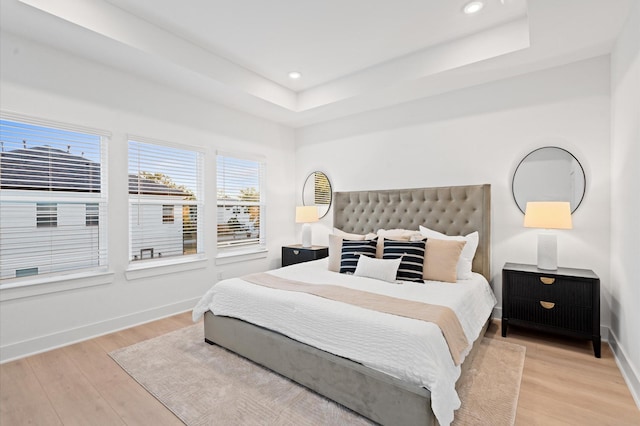 bedroom with a raised ceiling and light hardwood / wood-style flooring