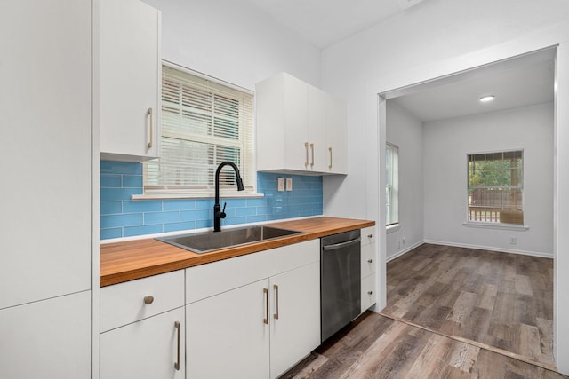 kitchen with decorative backsplash, butcher block counters, dark wood-style flooring, stainless steel dishwasher, and a sink