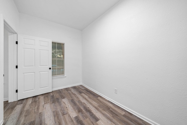 spare room featuring lofted ceiling and hardwood / wood-style flooring