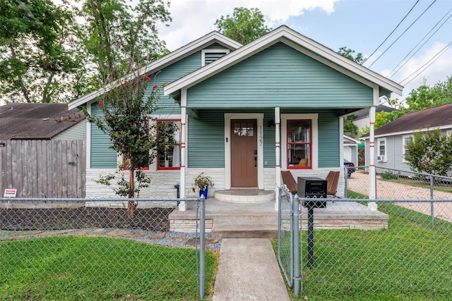 bungalow-style home with a front yard and covered porch