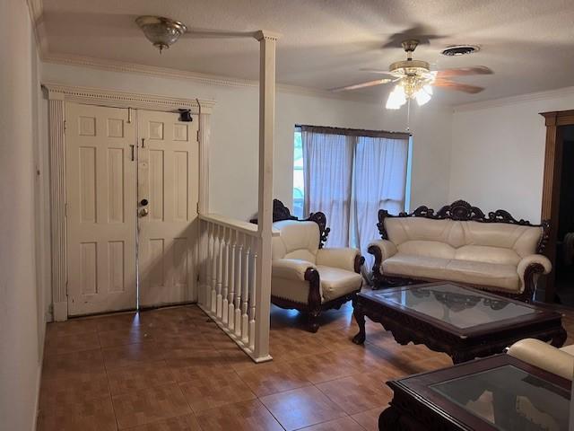 tiled living room with ceiling fan, crown molding, and a textured ceiling