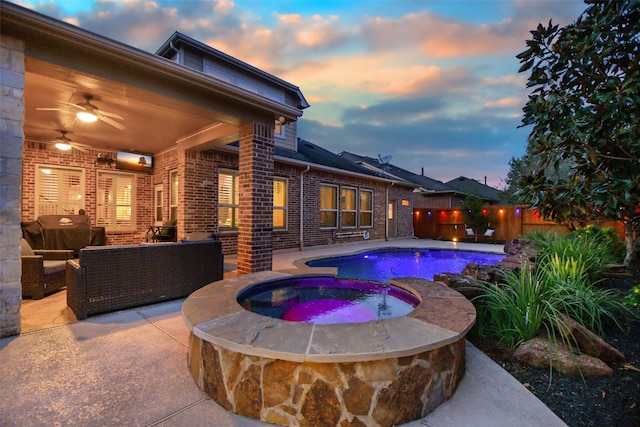 pool at dusk featuring an in ground hot tub, an outdoor hangout area, ceiling fan, and a patio area