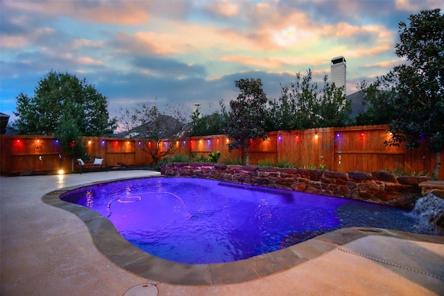 pool at dusk with pool water feature and a patio