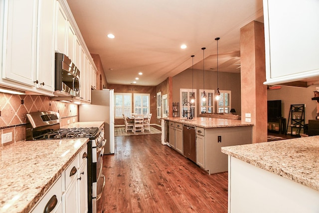 kitchen featuring appliances with stainless steel finishes, light stone counters, dark wood-type flooring, decorative light fixtures, and white cabinets