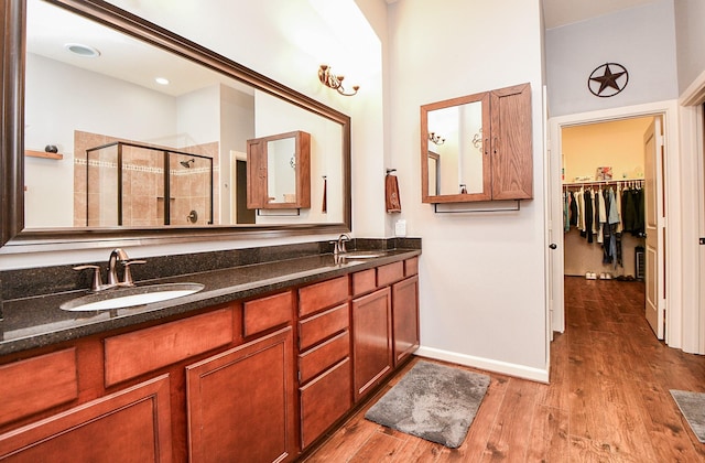 bathroom featuring a towering ceiling, vanity, wood-type flooring, and a shower with shower door