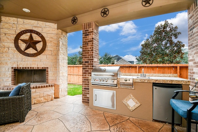 view of patio with an outdoor stone fireplace, exterior kitchen, sink, and grilling area