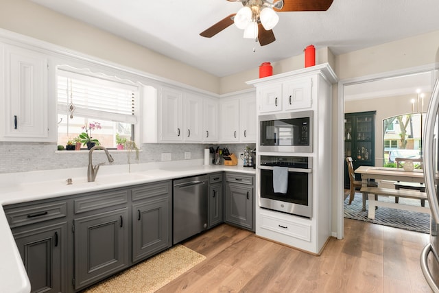 kitchen with appliances with stainless steel finishes, backsplash, gray cabinetry, sink, and white cabinetry